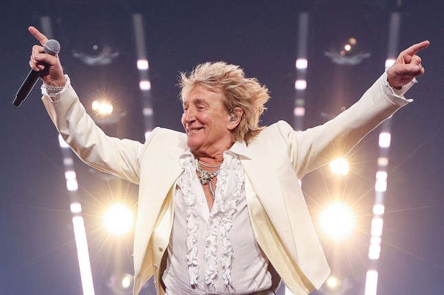 Sir Rod Stewart with hands in the air and white suit on