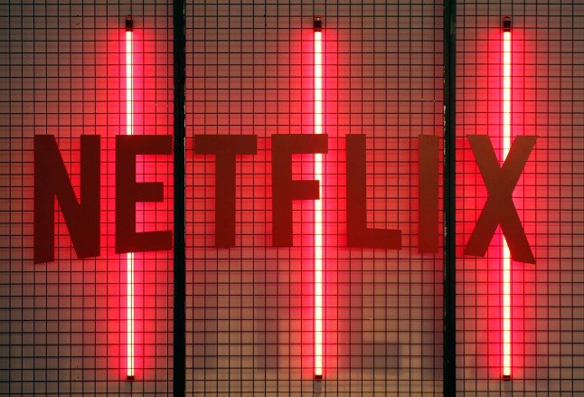 A red Netflix logo mounted on a wire cage with red strip lights behind it.