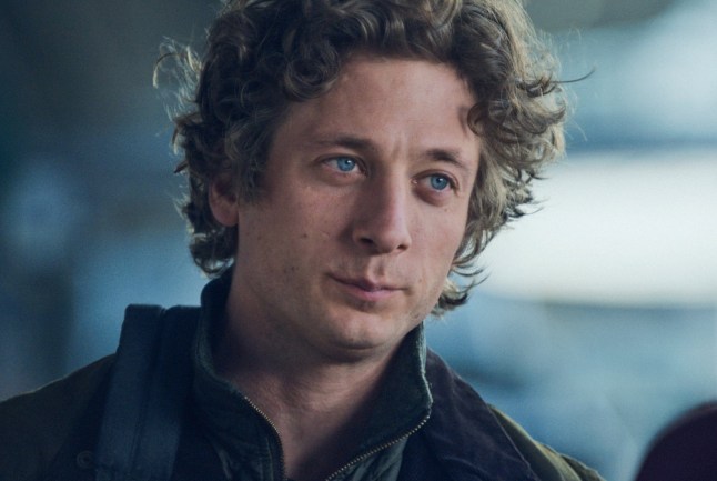 Jeremy Allen White as Carmy in a scene from The Bear. He has curly brown hair and wears a collared jacket.