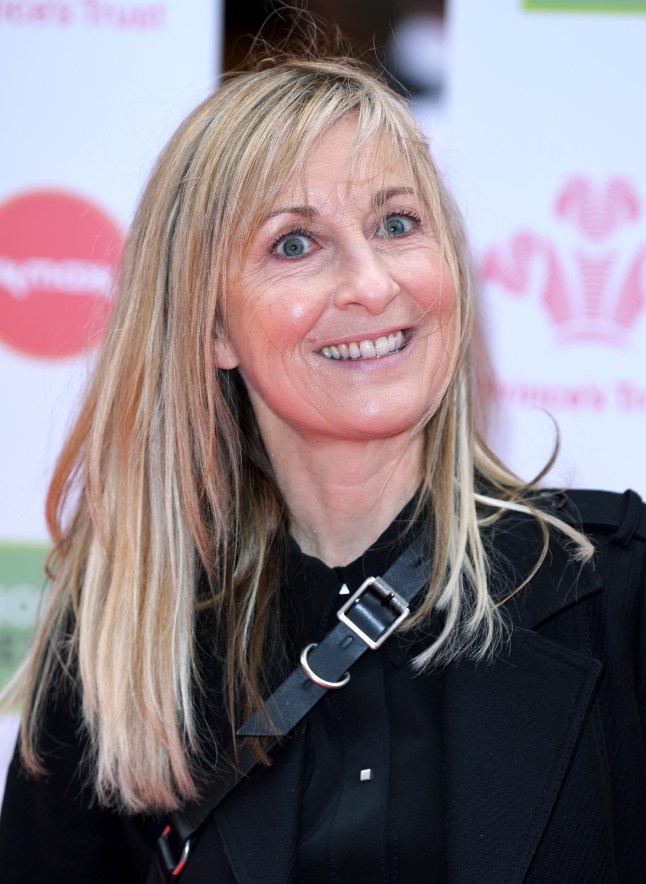 A close up of Fiona Phillips wearing a black jumper and a side bag