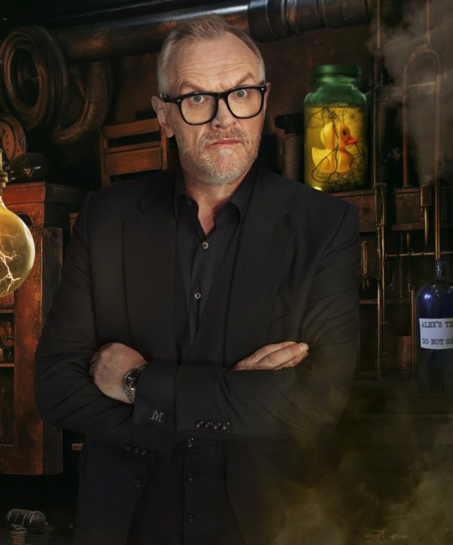 Greg Davies in black suit with his arms folded