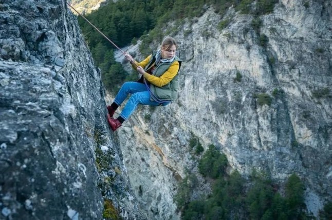 A still of the girl rope climbing down a cliff