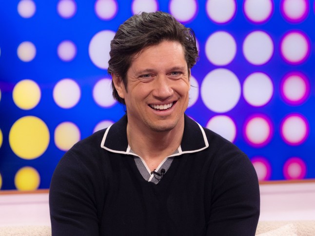 Vernon Kay with a colourful spotted background behind him