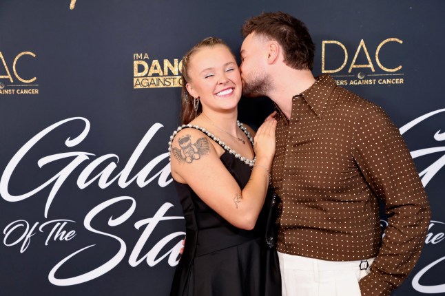 Chris Hughes kissing JoJo Siwa on the cheek at a red carpet event.