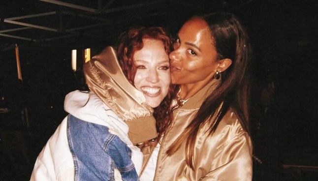 Alex Scott with her arm around Jess Glynne, giving her a kiss.