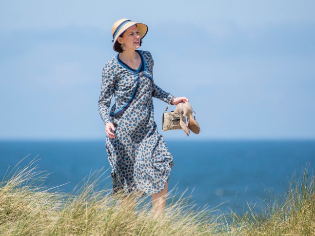 A scene from Seaside Hotel with a woman next to the sea holding her shoes.