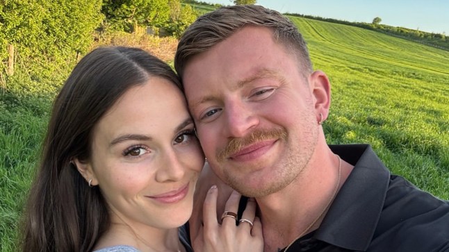 A selfie of Adam Peaty and Holly Ramsay smiling while stood in a field.
