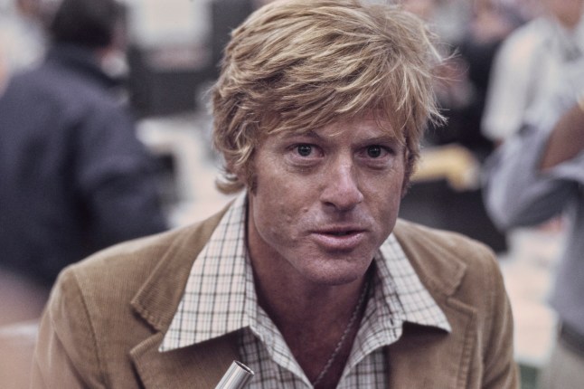 American actor Robert Redford, wearing a brown corduroy blazer over a checked shirt, in a recreation of The Washington Post's offices, on the set of 'All the President's Men,' filmed at Burbank Studios in Burbank, California, 1976. The political thriller based on the Watergate scandal, directed by Alan J Pakula, starred Redford as Bob Woodward. (Photo by Michael Montfort/Michael Ochs Archives/Getty Images)