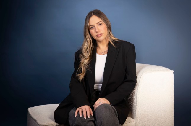 Holly Hagan from Geordie Shore wears a blazer and sits on a white chair.
