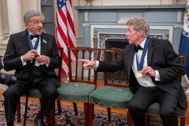 The 2025 Kennedy Center Honorees Sylvester Stallone, left, and Michael Crawford talk about their medallions as they gather for group photo at the 48th Kennedy Center Honors Medallion Reception, hosted at the U.S. Department of State, Saturday, Dec. 6, 2025 in Washington. (AP Photo/Kevin Wolf)